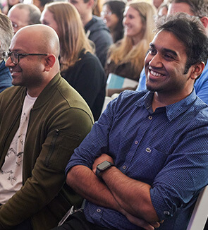 Two men in the audience at a conference smiling.